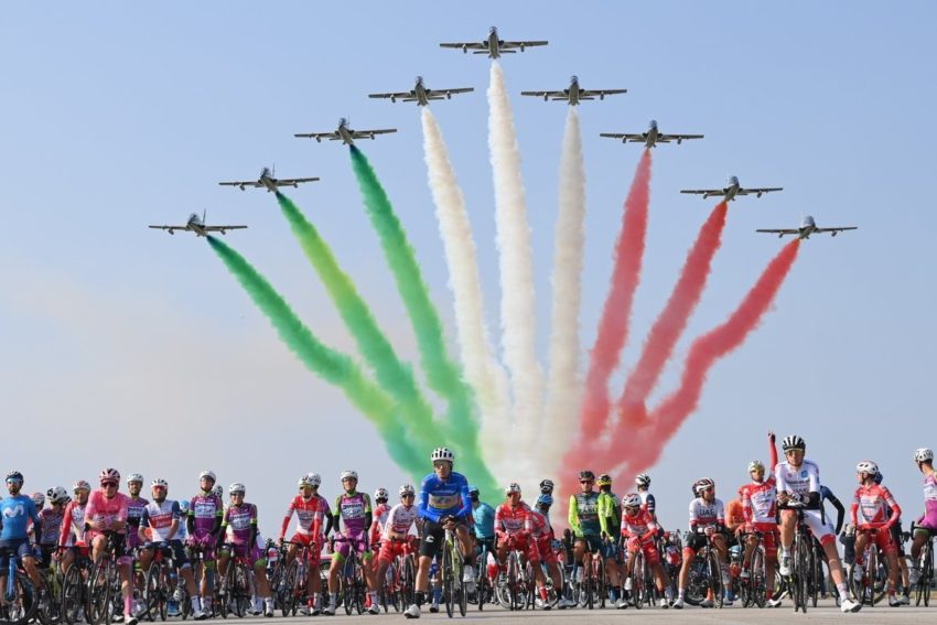Esquadrilha Frecce Tricolori de caças solta fumaça nas cores da bandeira da Itália na largada de prova no Giro